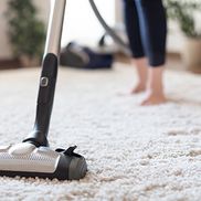 A woman hoovering a carpet