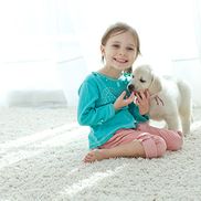 A young child and dog sitting on a carpet